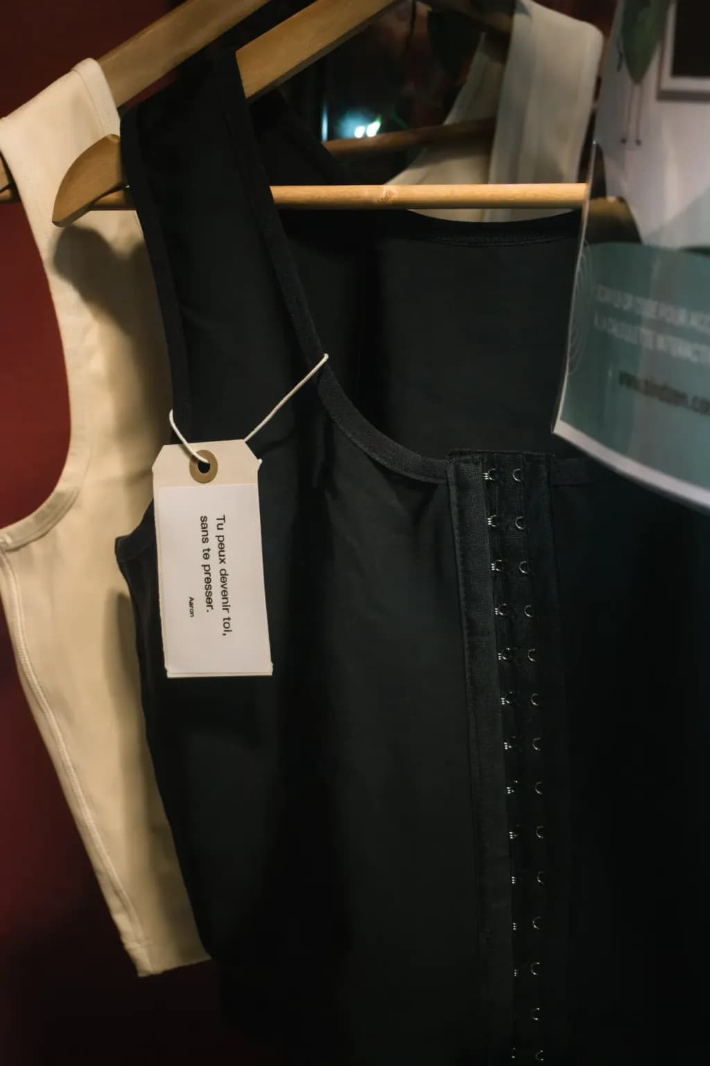 Binder Bindzen noir suspendu à un cintre, avec une étiquette « Tu peux devenir toi, sans te presser. »